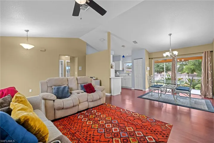 Living area with wood finished floors, vaulted ceiling, a chandelier, and a ceiling fan