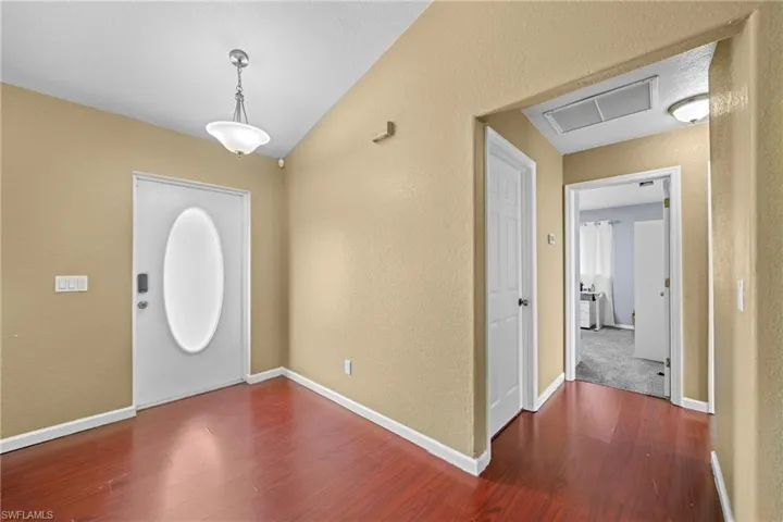 Foyer with wood finished floors, a textured wall, and baseboards