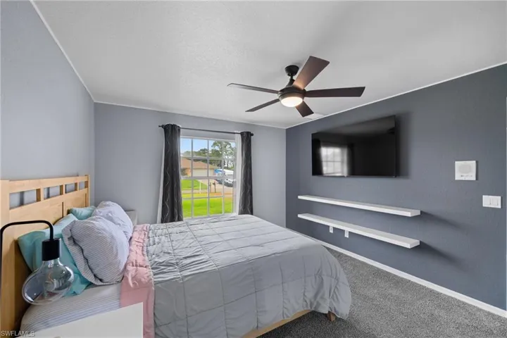 Carpeted bedroom with a ceiling fan, baseboards, and a textured ceiling
