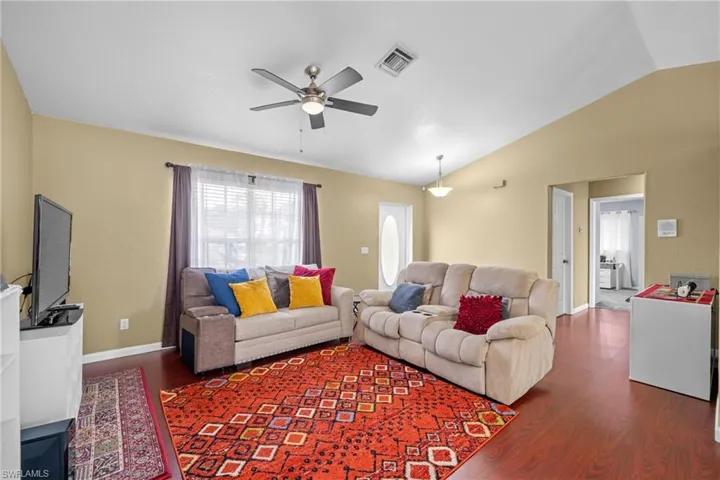 Living area featuring lofted ceiling, wood finished floors, ceiling fan, and baseboards