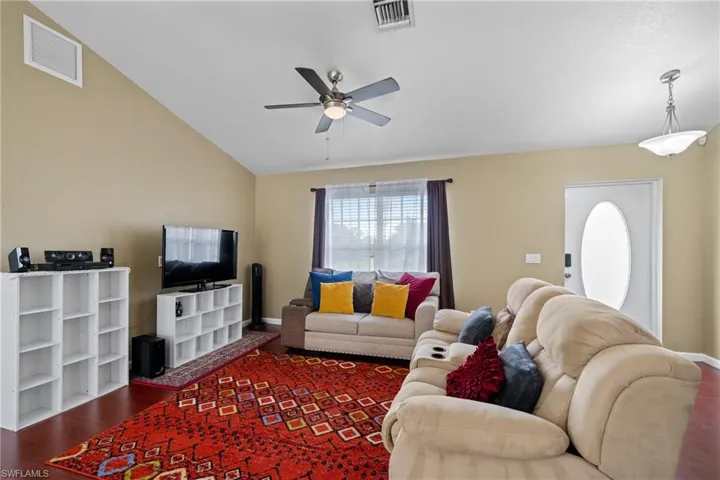 Living room featuring wood finished floors, ceiling fan, lofted ceiling, and baseboards