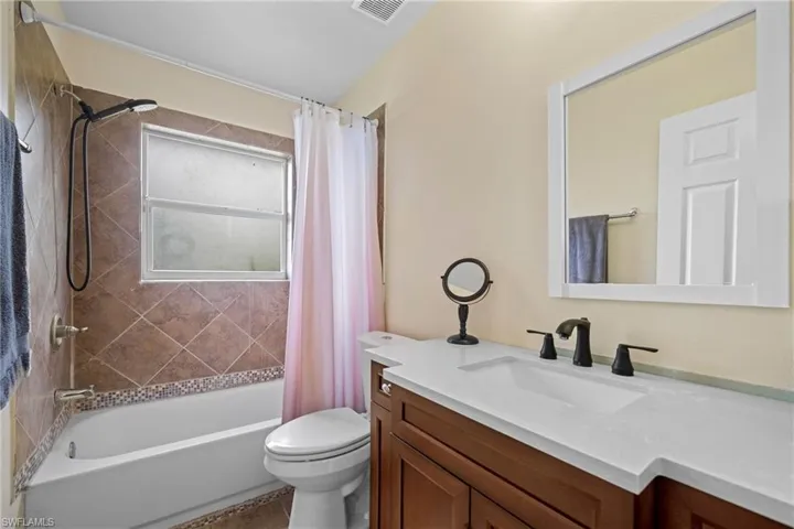 Bathroom with toilet, shower / tub combo with curtain, and vanity