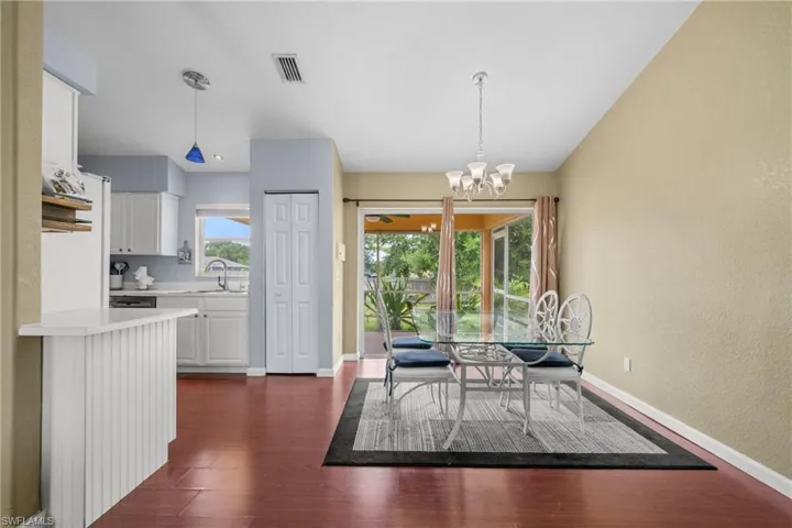 Dining area featuring a chandelier, dark wood-style flooring, baseboards, and a textured wall
