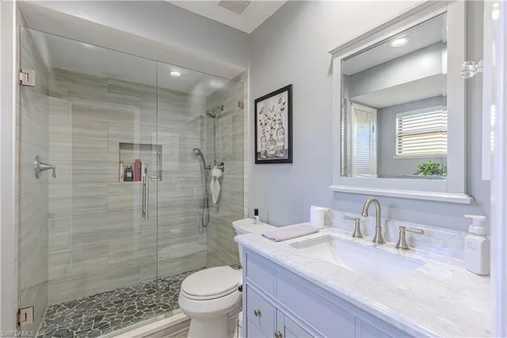 Bathroom featuring vanity, toilet, and a shower with door