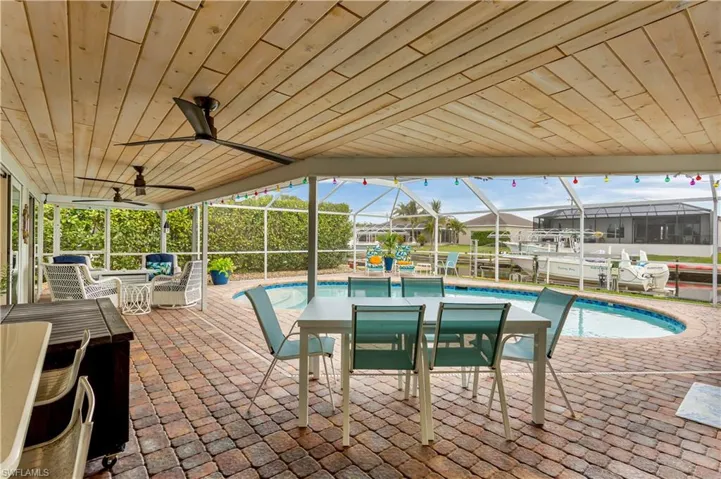 View of swimming pool with screened enclosure, ceiling fan, and a patio area