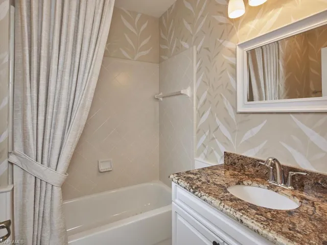 Guest bathroom featuring beautifulgranite countertops and a shower with tub. A must-have for buyers with kids and grandkids!