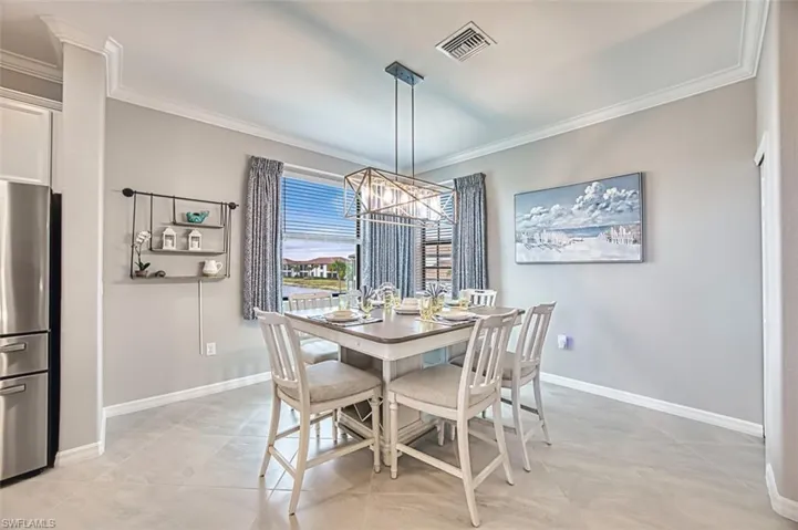Dining area featuring ornamental molding, a chandelier, and light tile patterned floors with lake view