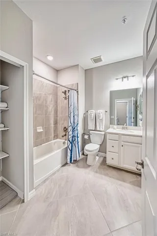 Bathroom featuring vanity, shower / tub combo, light tile patterned floors, and a textured wall