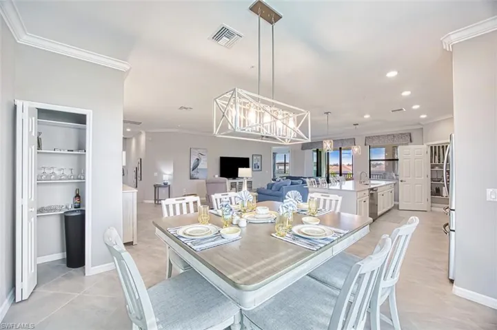 Dining area with crown molding, a chandelier, recessed lighting, and light tile patterned floors