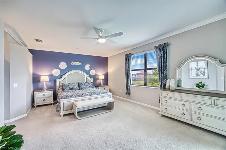 Primary Bedroom featuring crown molding, light colored carpet, and ceiling fan