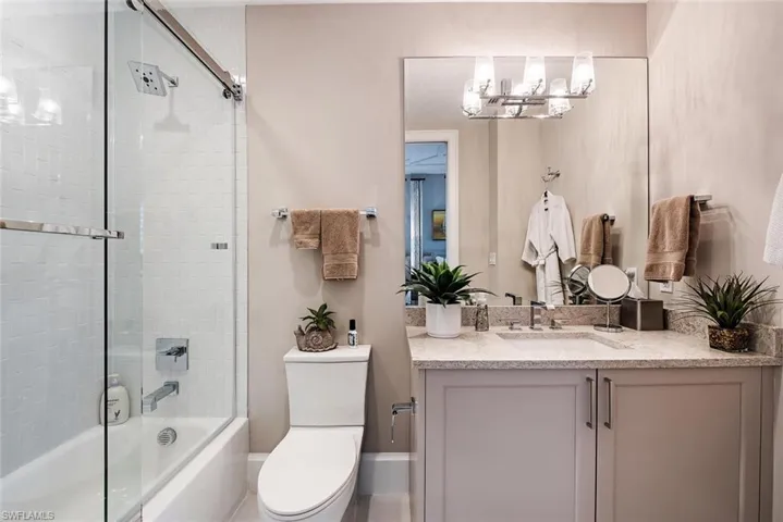 Full bathroom with a notable chandelier, combined bath / shower with glass door, toilet, and vanity