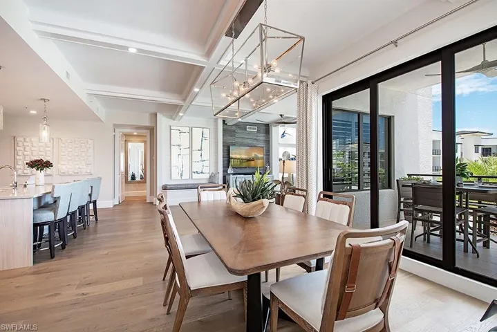 Dining space with beam ceiling, coffered ceiling, light hardwood / wood-style floors, and a chandelier
