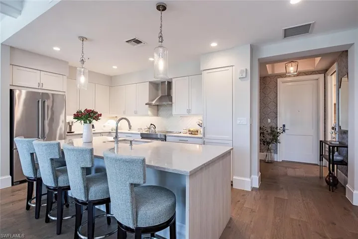 Kitchen featuring white cabinetry, wall chimney range hood, dark hardwood / wood flooring, and sink