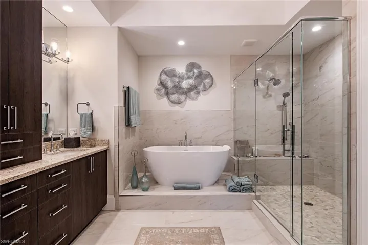 Bathroom featuring tile floors, tile walls, shower with separate bathtub, and large vanity