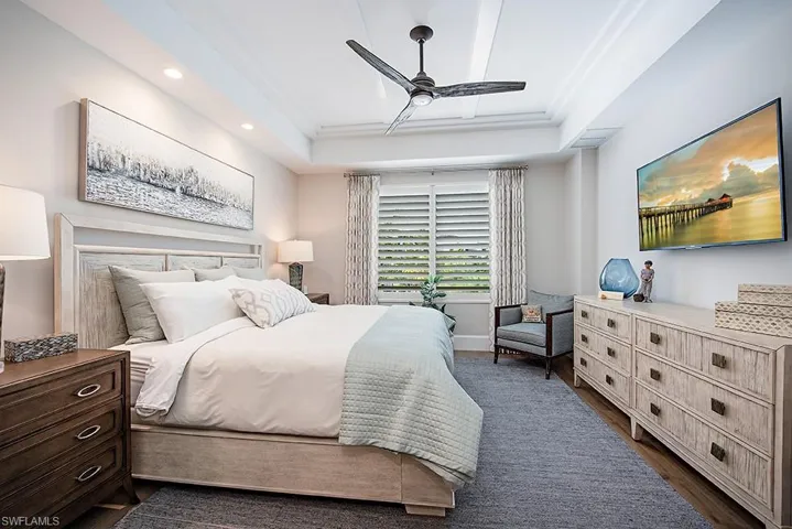 Bedroom featuring ceiling fan, dark hardwood / wood-style flooring, and a tray ceiling