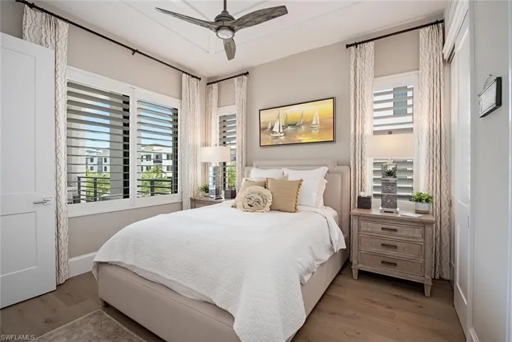Bedroom with wood-type flooring, ceiling fan, and multiple windows