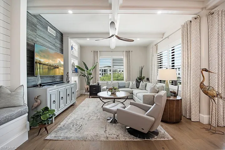 Living room with coffered ceiling, ceiling fan, beamed ceiling, and hardwood / wood-style flooring