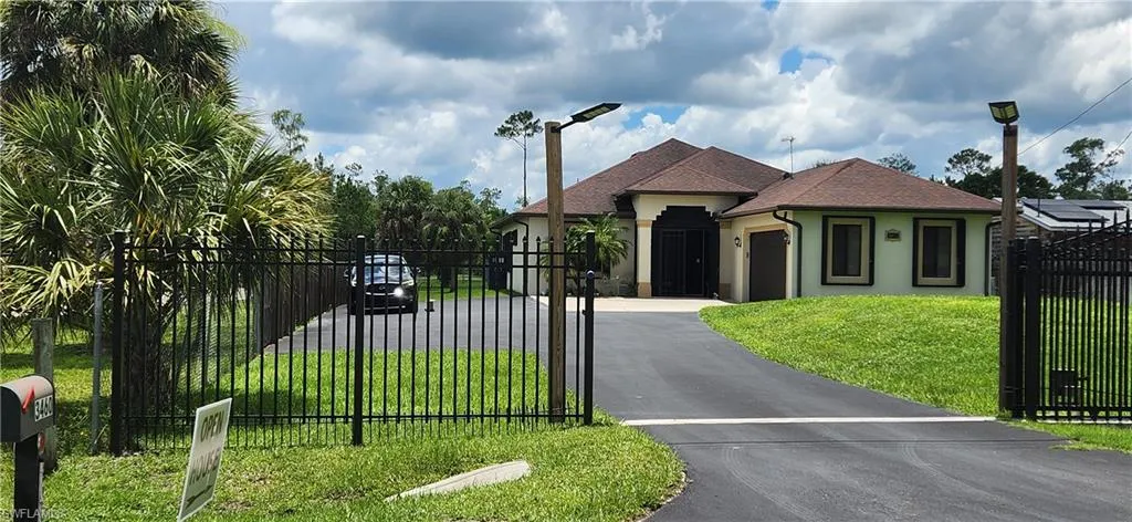 View of front of home with asphalt driveway, a garage, stucco siding, a gate, and a fenced front yard