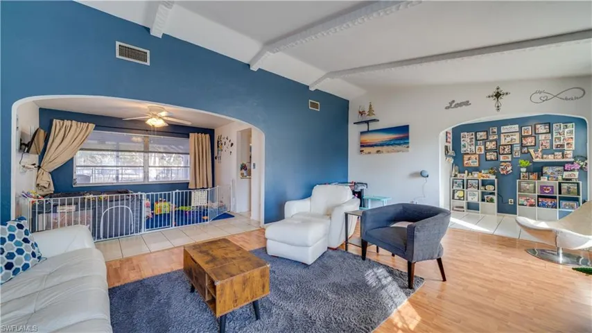 Living room featuring ceiling fan, vaulted ceiling, arched walkways, and wood finished floors