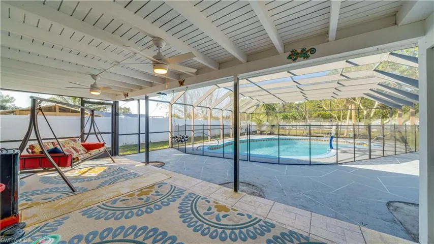 View of swimming pool with a sunroom, glass enclosure, a fenced backyard, and a patio