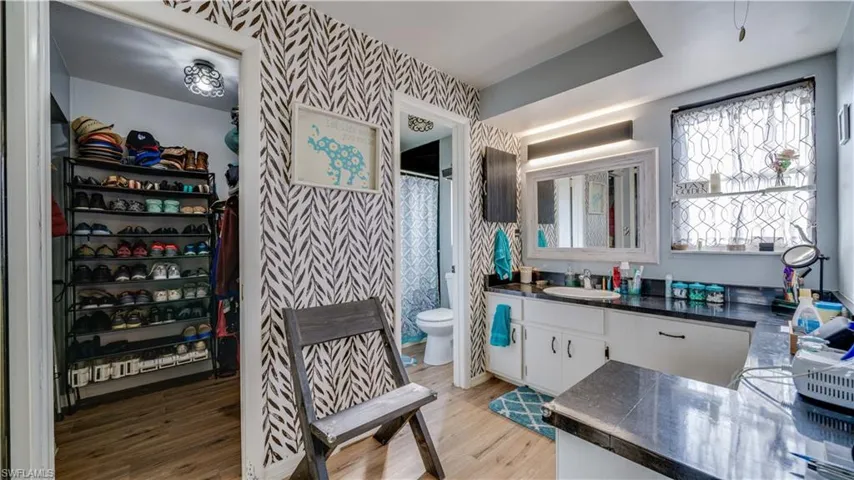 Full bathroom featuring wallpapered walls, a walk in closet, curtained shower, vanity, and light wood finished floors