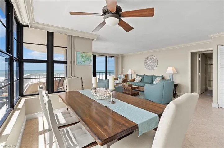 Tiled dining room featuring ceiling fan, expansive windows, a water view, and ornamental molding