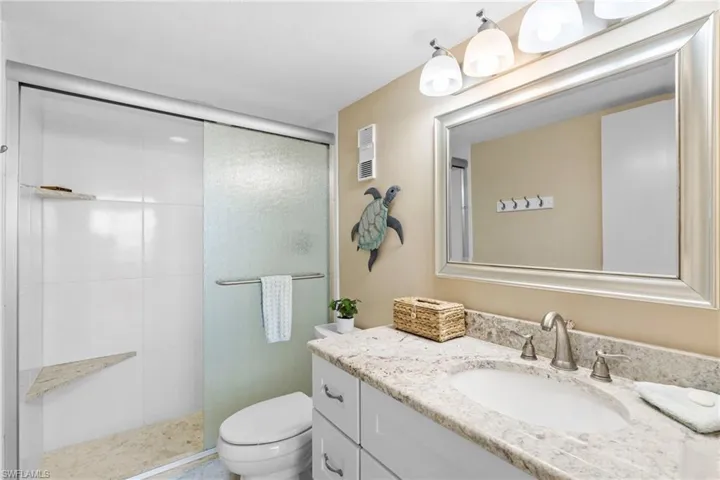 Bathroom with a shower with door, vanity, and toilet