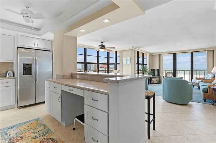 Kitchen with ceiling fan, fridge, a raised ceiling, and a wealth of natural light