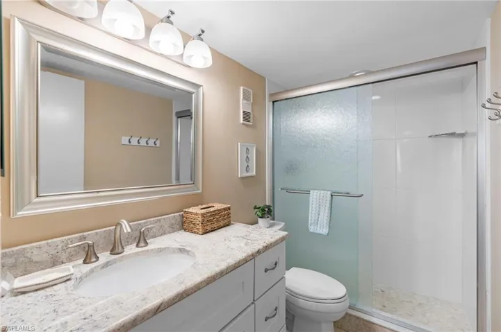 Bathroom with toilet, vanity, and an enclosed shower