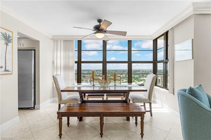 Tiled dining space featuring ceiling fan and ornamental molding