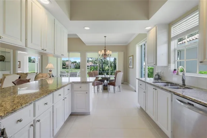 Kitchen featuring stainless steel dishwasher, a sink, a chandelier, white cabinetry, and ornamental molding