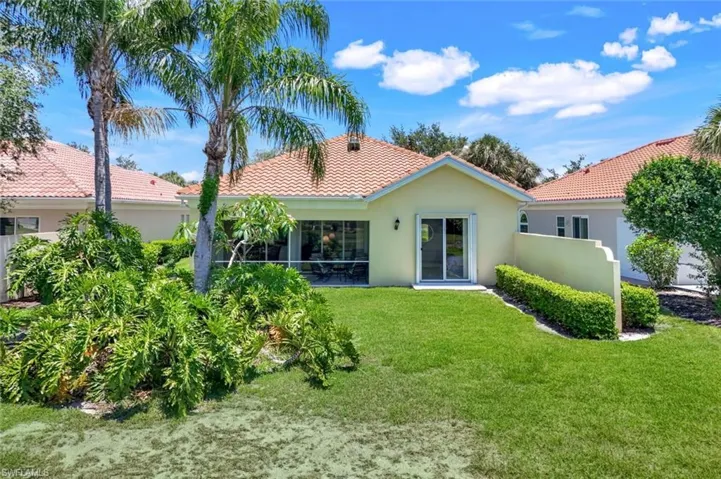Back of property with stucco siding, a tiled roof, and a yard