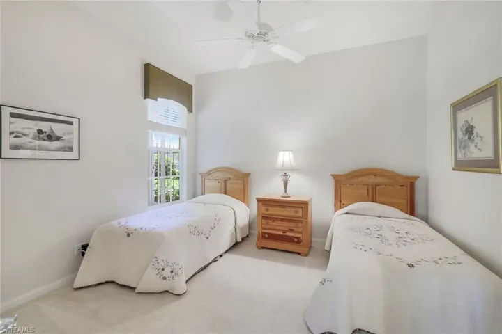 Bedroom with light colored carpet, baseboards, and ceiling fan