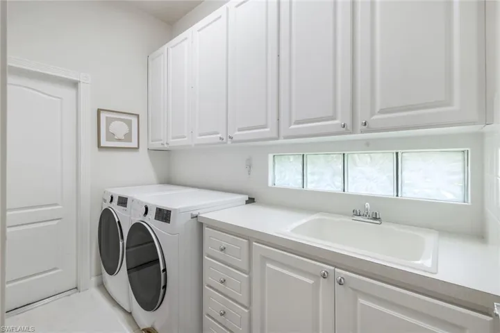 Washroom featuring cabinet space, washer and clothes dryer, and light tile patterned floors