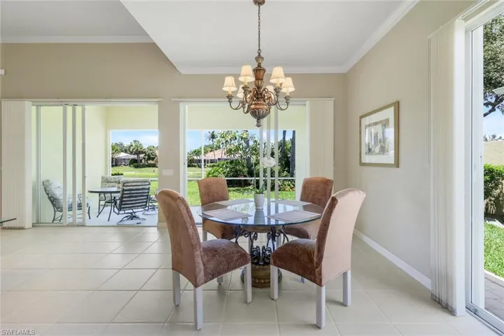 Dining area featuring a chandelier, light tile patterned flooring, crown molding, and baseboards