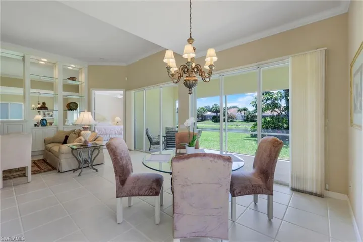 Dining room with a chandelier, crown molding, light tile patterned floors, and built in shelves