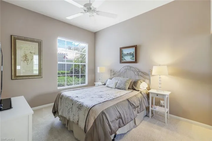 Bedroom featuring light colored carpet, baseboards, and a ceiling fan