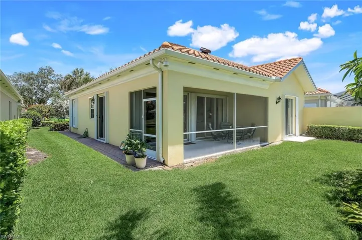 Rear view of house with a tiled roof, a lawn, stucco siding, and a sunroom
