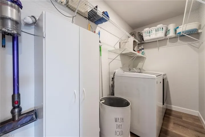 Washroom featuring dark wood-style flooring and washing machine and clothes dryer