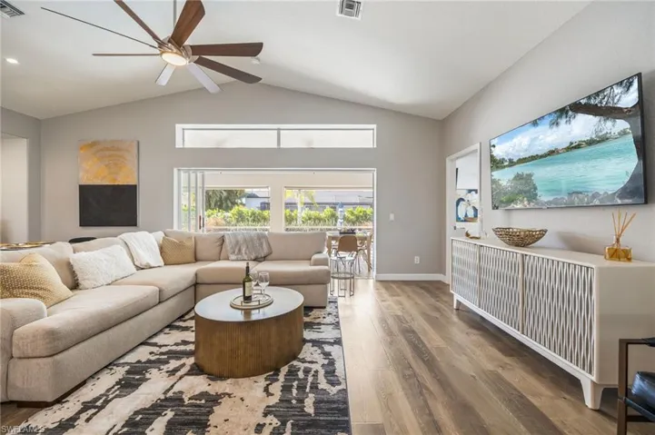 Living room with wood finished floors, vaulted ceiling, and ceiling fan