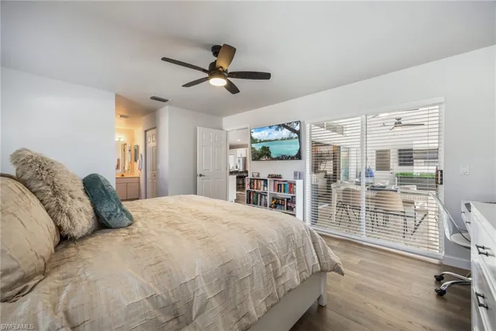 Bedroom featuring ensuite bath, ceiling fan, and dark wood finished floors