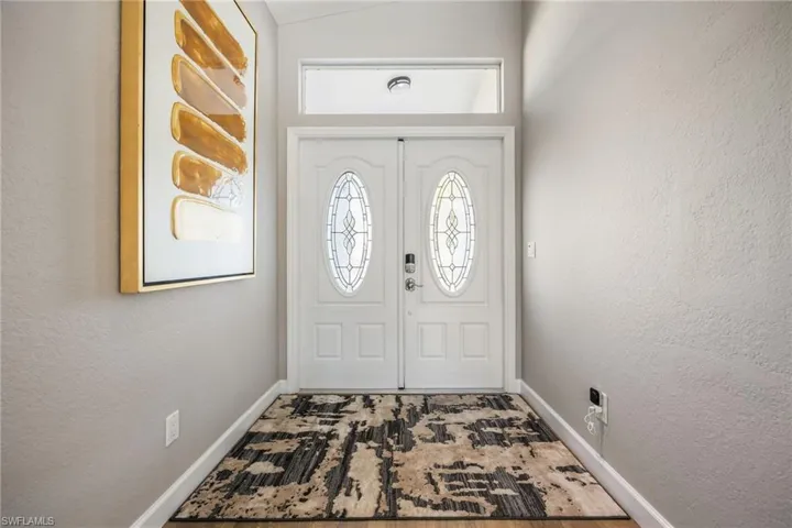 Foyer entrance with a textured wall and baseboards