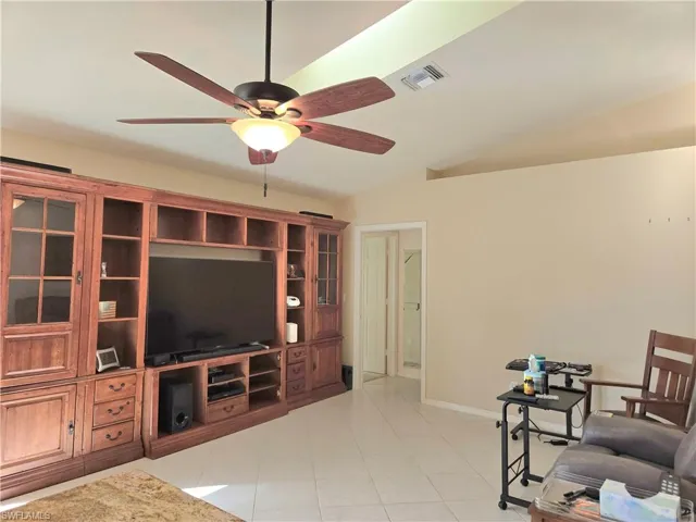 Tiled living room featuring ceiling fan and vaulted ceiling