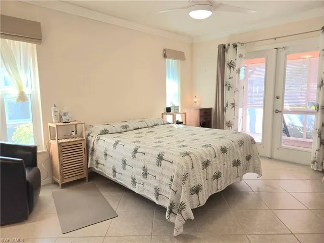 Tiled bedroom featuring ceiling fan, crown molding, and french doors