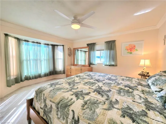 Bedroom featuring carpet, ceiling fan, and crown molding