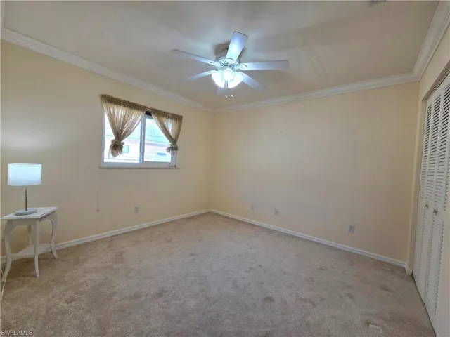 Unfurnished bedroom with light carpet, a closet, ceiling fan, and crown molding