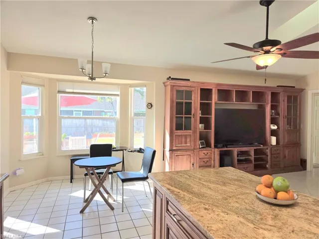 Kitchen featuring a wealth of natural light, light tile patterned floors, hanging light fixtures, and ceiling fan with notable chandelier
