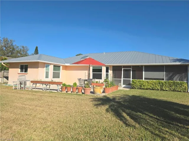 Rear view of property featuring a lawn and a sunroom