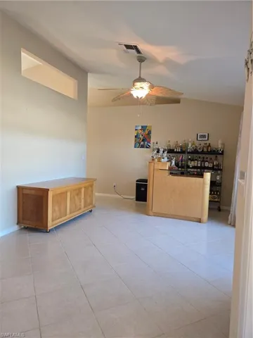 Tiled spare room with ceiling fan and indoor bar