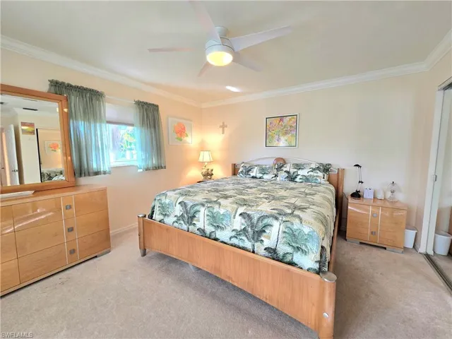 Carpeted bedroom featuring ceiling fan and crown molding